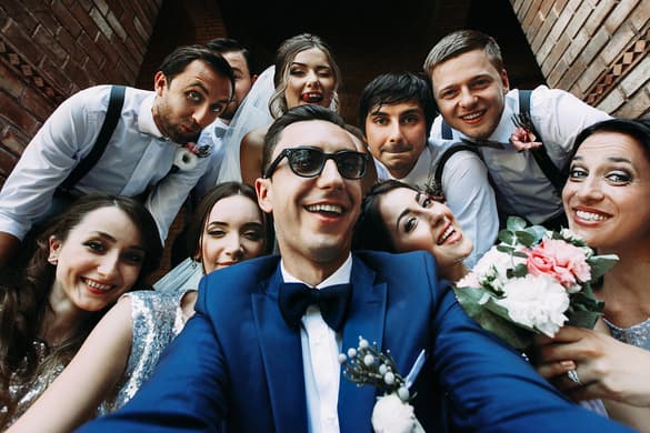 bride and groom taking a fun photo with wedding party