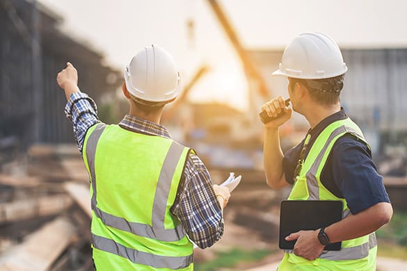 construction workers observe a job site at sunset