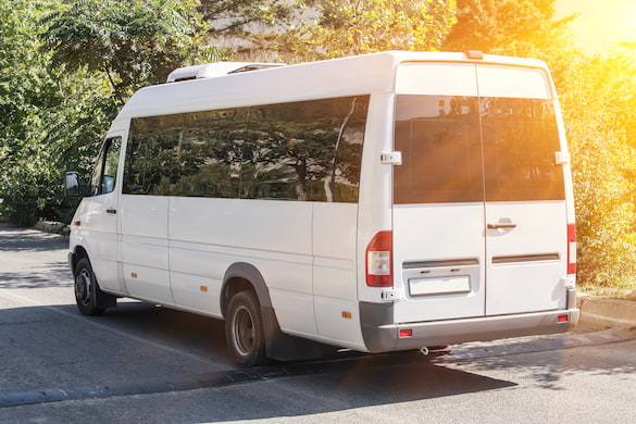 a small white minibus, with the sun shining in the background