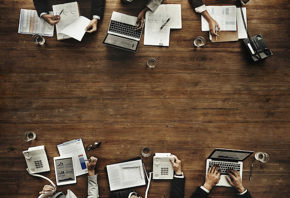 computers and notebooks spread across a table during a business meeting